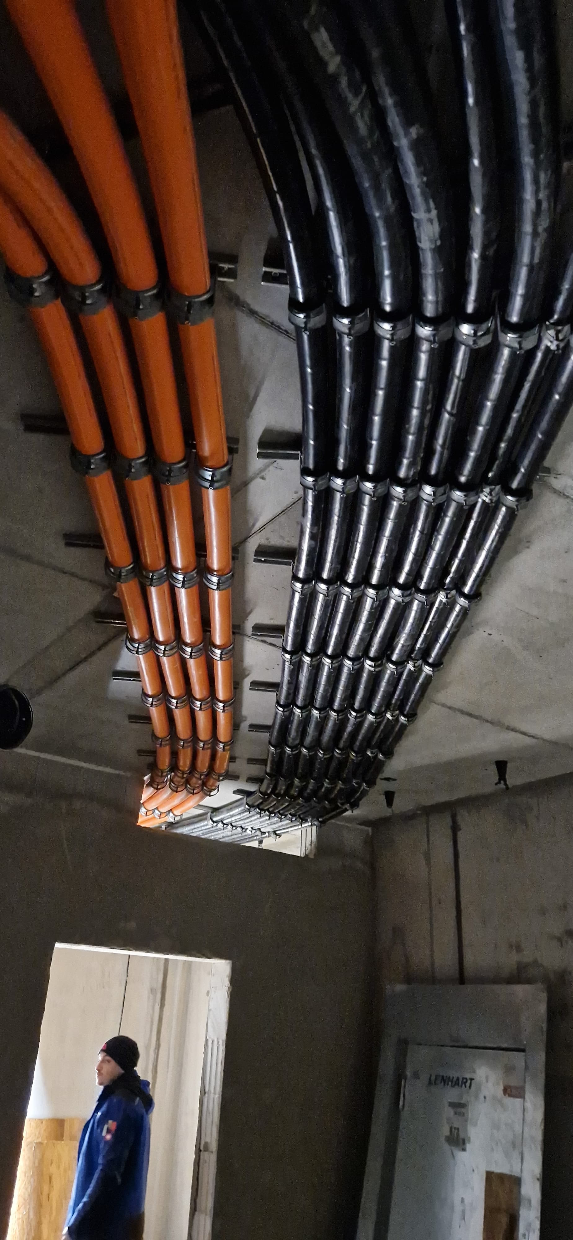 Mehrere Kabel werden durch vorbereitete Wanddurchführungen im Rohbau geführt