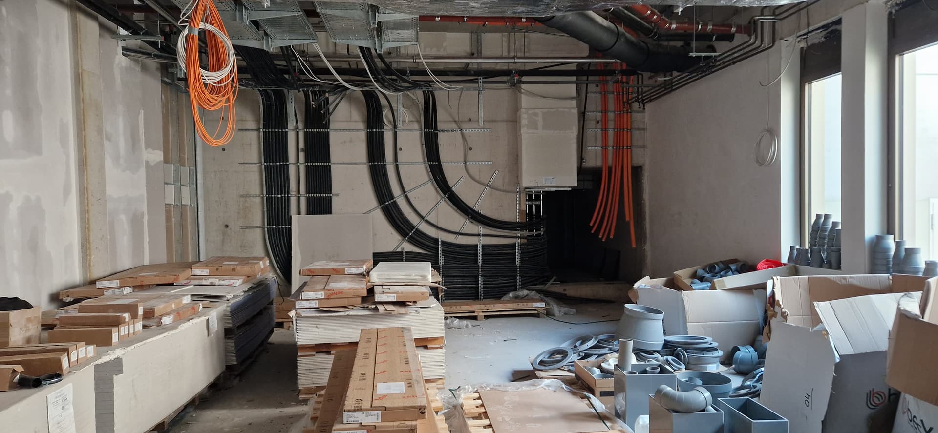 Mehrere Stromkabel führen durch eine Wand in einen Technikraum